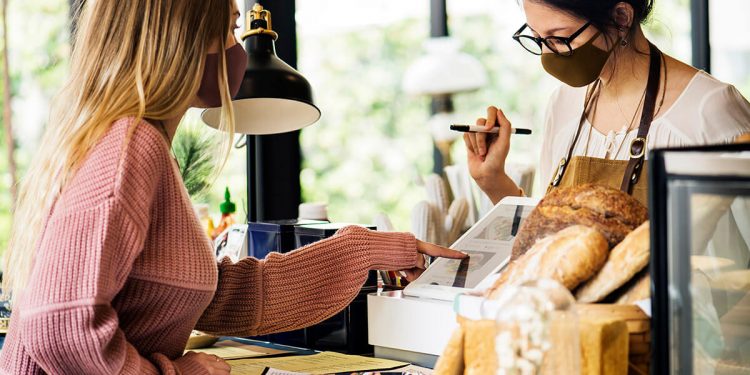 Mujer pagando con mascarilla